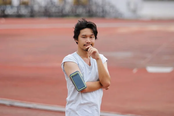 Retrato de joven fitness Hombre asiático mirando a la cámara y de pie en la pista en el estadio — Foto de Stock