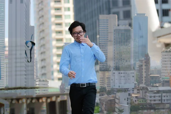 Başarılı iş kavramı. Yürüyüş ve onun kravat içinde kentsel atma mutlu genç Asyalı işadamı çift pozlama şehir arka bina.