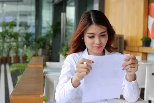 Счастливая деловая женщина смотрит карты в руках в офисе — стоковое фото