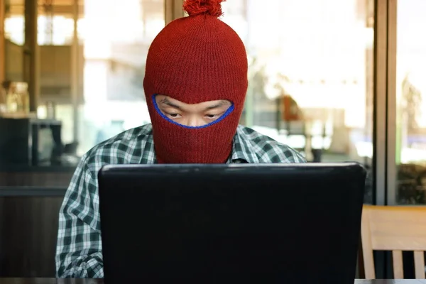 Masked hacker wearing a balaclava stealing information data with laptop. Computer criminal concept. — Stock Photo, Image
