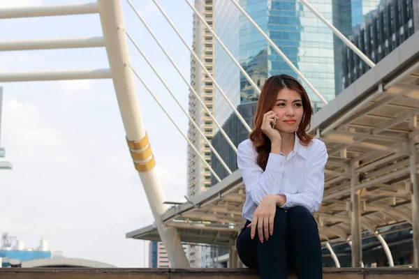 Young attractive Asian lady talking on phone at urban building with copy space background. — Stock Photo, Image