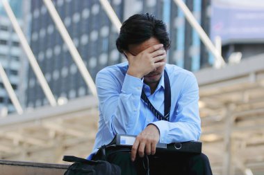 Sinirli stresli genç Asya iş adamı Önden Görünümü Kapat gözlerini. o duygu zorlanma ya da çalıştı ve şehir arka plan, baş ağrısı.