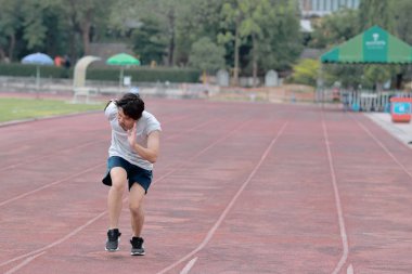 Yakışıklı sporcu Asya Stadyumu kopya alan arka plan ile yarış pisti üzerinde koşan adam. Sağlıklı aktif yaşam tarzı kavramı.