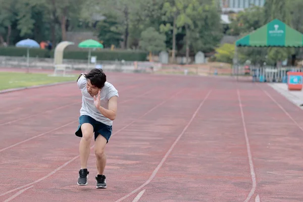 Yakışıklı sporcu Asya Stadyumu kopya alan arka plan ile yarış pisti üzerinde koşan adam. Sağlıklı aktif yaşam tarzı kavramı.