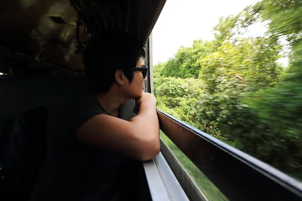 Tono de imagen de tono bajo. Amplio ángulo de tiro de joven turista asiático mirando la naturaleza vista desde las ventanas del tren . — Foto de Stock