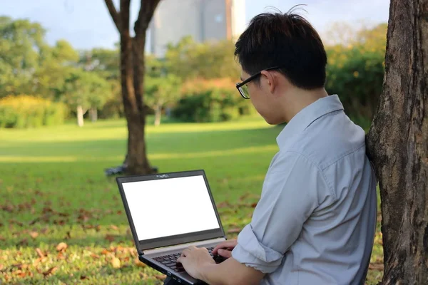 Ganteng pemuda bekerja dengan laptop komputer untuk karyanya di taman kota . — Stok Foto