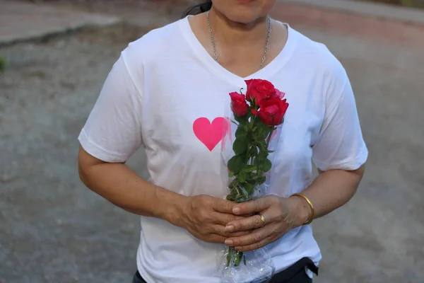 Mujer asiática de mediana edad está sosteniendo un hermoso ramo de rosas rojas. Amor y romance Concepto de San Valentín . —  Fotos de Stock