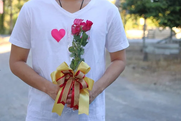 Букет красивых красных роз держит молодой красивый мужчина в белой рубашке. День Святого Валентина или концепция знакомств — стоковое фото