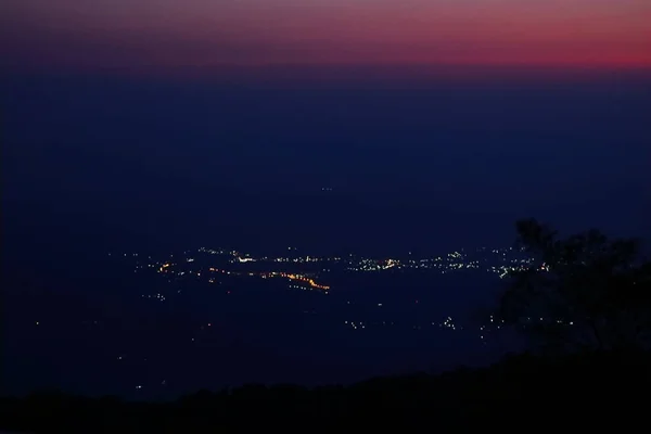 Vista nocturna de la ciudad después de la puesta del sol desde el punto de vista en la cima de la montaña —  Fotos de Stock