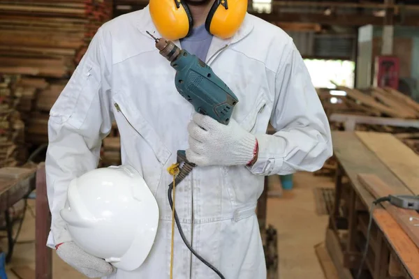 Porträt eines Arbeiters in Schutzuniform mit Elektrobohrmaschine in der Tischlerei. — Stockfoto