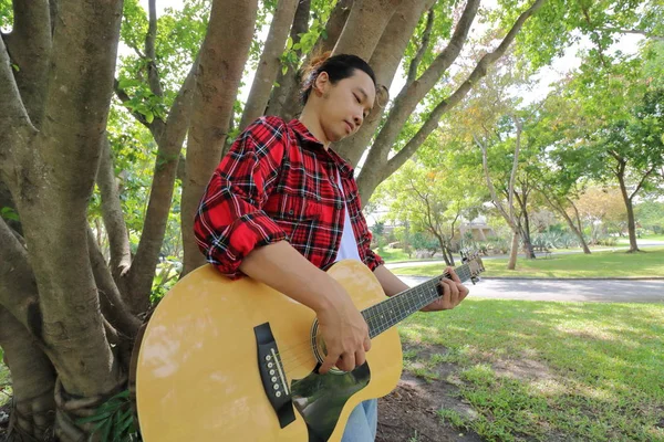 Geniş açı çekim yakışıklı genç adamın akustik gitar güzel doğa arka planda müzik çalma. — Stok fotoğraf