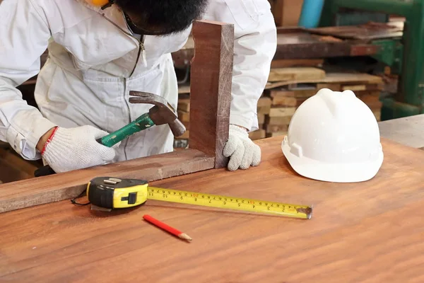 Professioneller Tischler mit Sicherheitsuniform, der Hammer mit anderen Werkzeugen in der Tischlerei hält. — Stockfoto