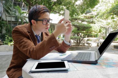 Geniş açı çekim yakışıklı iş adamı onun smartphone parkta açık havada onun iş arıyorum