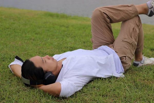 Портрет юнак азіатських лежачи на зеленої трави в природі фон Розслабся час. — стокове фото
