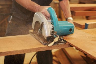 Elektrik daire testere üst düzey marangoz marangozluk atölye eller karşı ahşap bir parça kesilir.
