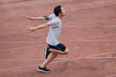 Stadyumda yolda bitiş çizgisine çapraz atletik yakışıklı genç Asyalı atlet Sprinterlerin bulanık soyut.