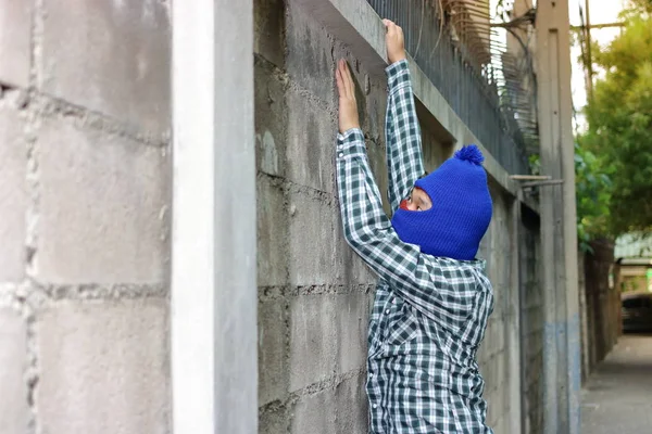 Rånare i en mask som klättring genom ett staket — Stockfoto