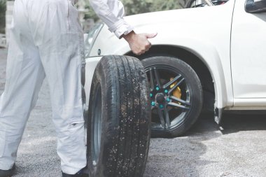 Yedek lastik hazırlanıyor taşıyan beyaz üniformalı otomotiv mekanik adam araba tekerlek değiştirin. Oto Tamir Servisi.
