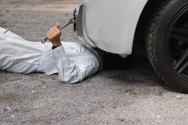 Yan görünüm mekanik aşağı yalan ve arabanın altına sabitleme beyaz üniformalı. Oto Tamir Servisi.
