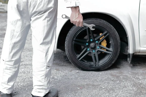 Visão traseira do mecânico automotivo confiante em uniforme branco segurando chave nas mãos pronto para reparar o motor do carro . — Fotografia de Stock