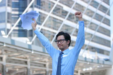 Grafikler veya evrak, Kentsel şehir arka plan ile el yetiştirme başarılı genç Asya iş adamı portresi.