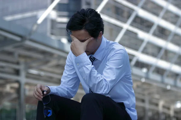 Frustriert nimmt der gestresste junge asiatische Geschäftsmann die Brille ab und schließt die Augen. er fühlt Anspannung oder erprobte Kopfschmerzen. — Stockfoto