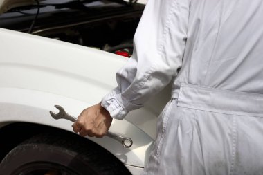 Seçici odak araba İngiliz anahtarıyla onarım garaj arka plan açık kukuleta holding profesyonel mekanik adamın ellerinde.