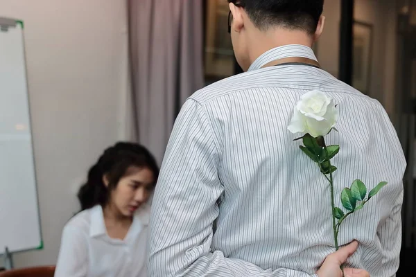 Молодой азиатский бизнесмен держит за спиной белую розу для неожиданной девушки в День Святого Валентина. Любовь и романтика в офисной концепции . — стоковое фото