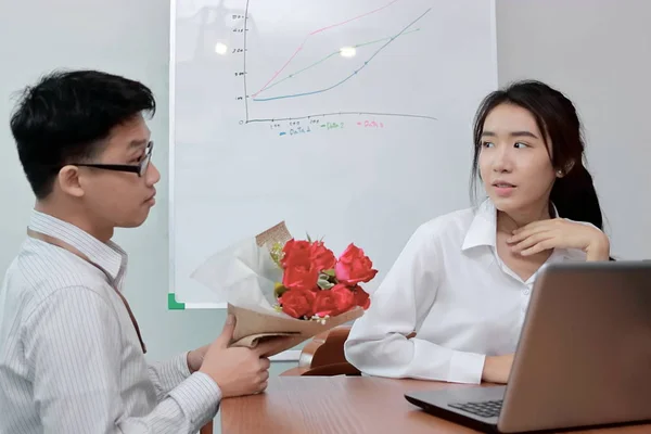 Jolie jeune femme asiatique acceptant un bouquet de roses rouges de petit ami au bureau le jour de la Saint-Valentin. Amour et romance dans le concept de lieu de travail. Concentration sélective et faible profondeur de champ . — Photo