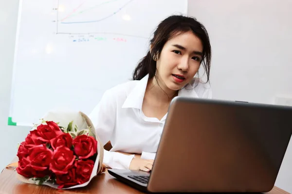Винтажный тонизирующий образ веселой молодой азиатской деловой женщины с букетом красных роз на рабочем столе. День святого Валентина . — стоковое фото