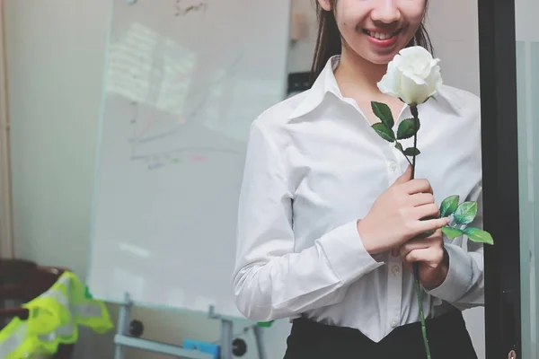 Винтажный тонизирующий образ веселой молодой азиатской деловой женщины, держащей в офисе белые розы в День Святого Валентина. Любовь и романтика в концепции рабочего места . — стоковое фото