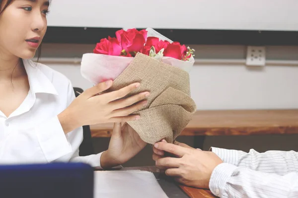 Обрезанный образ привлекательной молодой азиатки, принимающей букет красных роз от своего бойфренда в день Святого Валентина. Любовь и романтика в концепции рабочего места . — стоковое фото