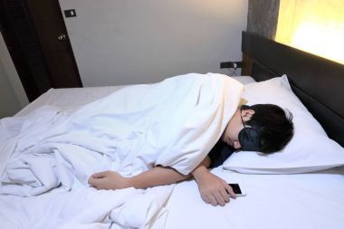 Genç Asyalı adam maskesi yatak yatak odasında gece uyku rahat çalıştı