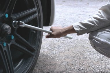 İngiliz anahtarı garajda araba lastiği değiştirmek için hazır holding beyaz üniformalı profesyonel mekanik eller yukarı kapatın.