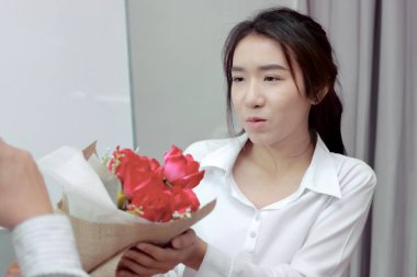 Çekici genç Asyalı kadın erkek Office kırmızı gül buketi Sevgililer Günü'nde kabul yumuşak odak noktası. Aşk ve romantizm işyeri kavramı içinde.