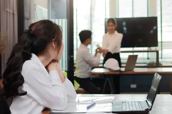 Завистливая злая азиатская деловая женщина, выглядящая любящей парой в офисе. Ревность и зависть в дружеских отношениях — стоковое фото