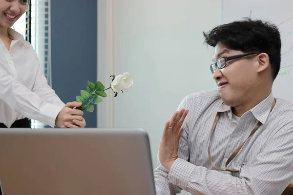 Soft focus angry Asian business man refuses a white roses from attractive woman. Disappointed love concept.