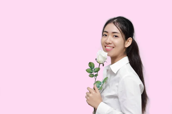 Portrait d'une jolie jeune femme asiatique tenant une rose blanche sur fond rose isolé. Concept de Saint-Valentin . — Photo