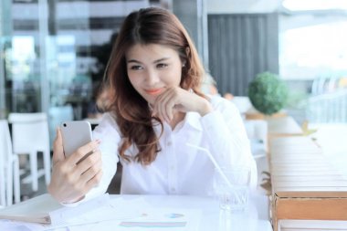 Arka plan veya dükkanda fotoğrafta selfie arasında oldukça Asya kadının elinde mobil akıllı telefon üzerinde seçici odak bulanık .