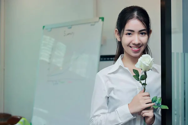 Винтажный тонизирующий образ привлекательной молодой азиатской бизнес-женщины, держащей в офисе белые розы в День Святого Валентина. Любовь и романтика . — стоковое фото