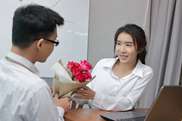 Счастливая молодая азиатка, принимающая букет красных роз от своего бойфренда в день Святого Валентина. Любовь и романтика в концепции рабочего места . — стоковое фото