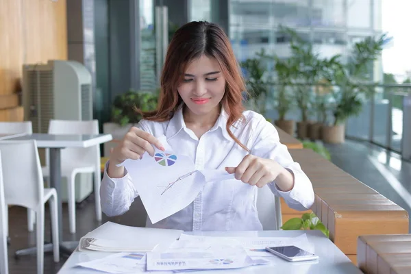 Крупный план молодой азиатской бизнес-женщины, разрывающей карты на столе в офисе — стоковое фото
