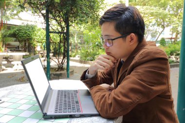 Ekran laptop arıyorum ve düşünme Asya genç iş adamı.