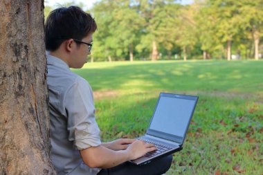 Genç adamın dinlendirici doğa park arka plan laptop ile arkadan görünüş.