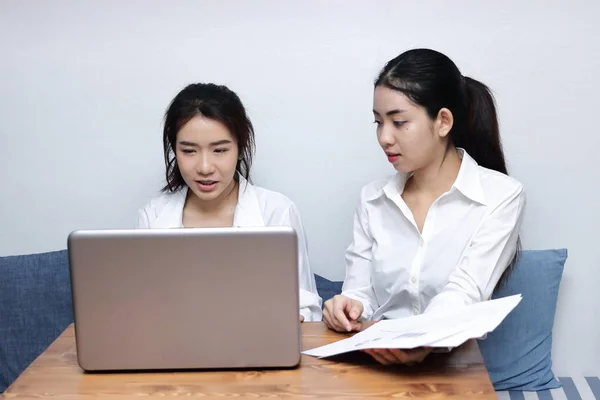 Две молодые азиатские бизнесвумен, работающие вместе за ноутбуком в офисе . — стоковое фото