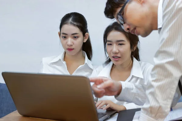 Молодые азиатские бизнесмены работают вместе за ноутбуком в офисе. Концепция мозгового штурма. Селективная фокусировка и мелкая глубина резкости . — стоковое фото