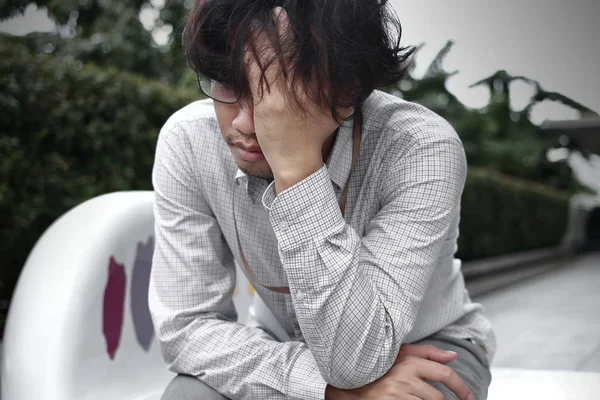 Sinirli stresli genç Asya iş adamı kafa dokunmaktan ve hayal kırıklığına veya iş ile yorgun hissediyorum elle önden görünümü. — Stok fotoğraf