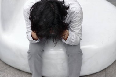 Havadan görünümü sinirli stresli genç Asyalı çalışan adam elleriyle yüzünü kaplayan ve hayal kırıklığına veya yorgun hissediyorum. İşsiz işadamı kavramı.