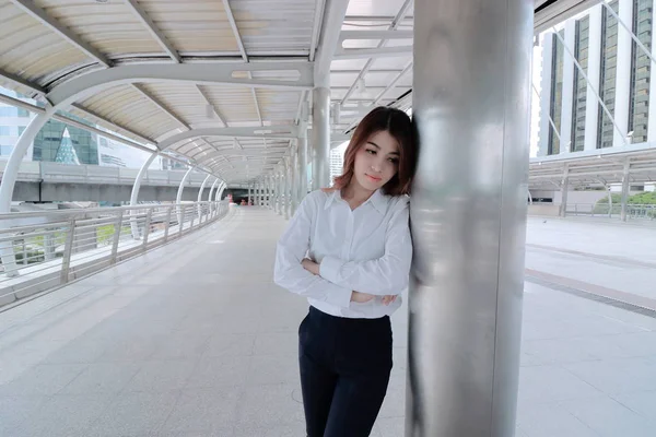 Wide angle shot of stressed young Asian busines woman leaning a pole at walkway outside office — Stock Photo, Image