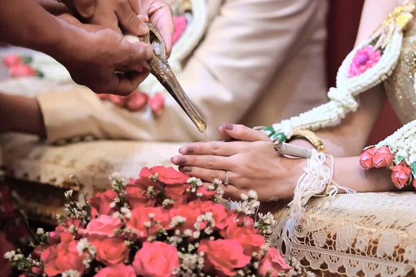 Mariée et marié mains dans l'eau cérémonie de relance. Mariage traditionnel thaï — Photo